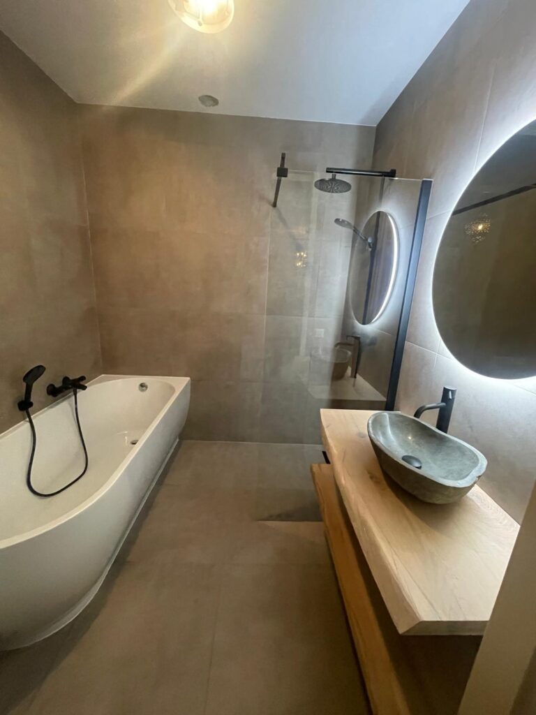 Gerenoveerde badkamer met vrijstaand bad, inloopdouche en ronde spiegel met verlichting